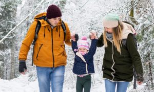 Family hiking through snow covered forest
