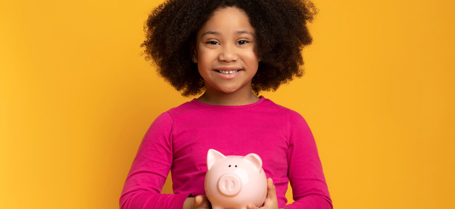 Young black girl smiling with piggy bank