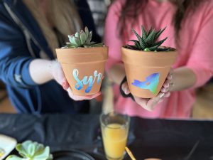 Artists holding decorated pots with succulents