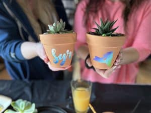 Artists holding decorated pots with succulents