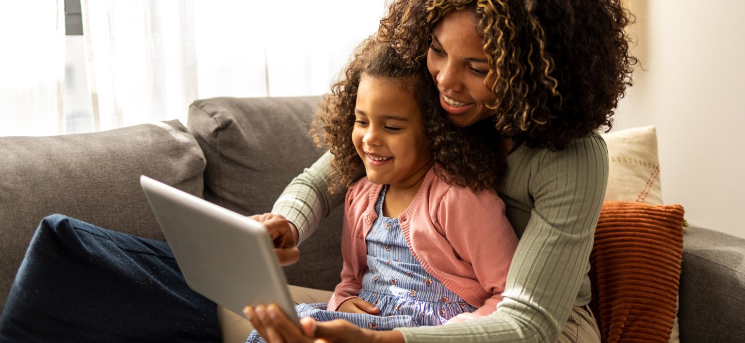Black mom showing daughter website on tablet