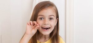 Young girl holding her lost tooth