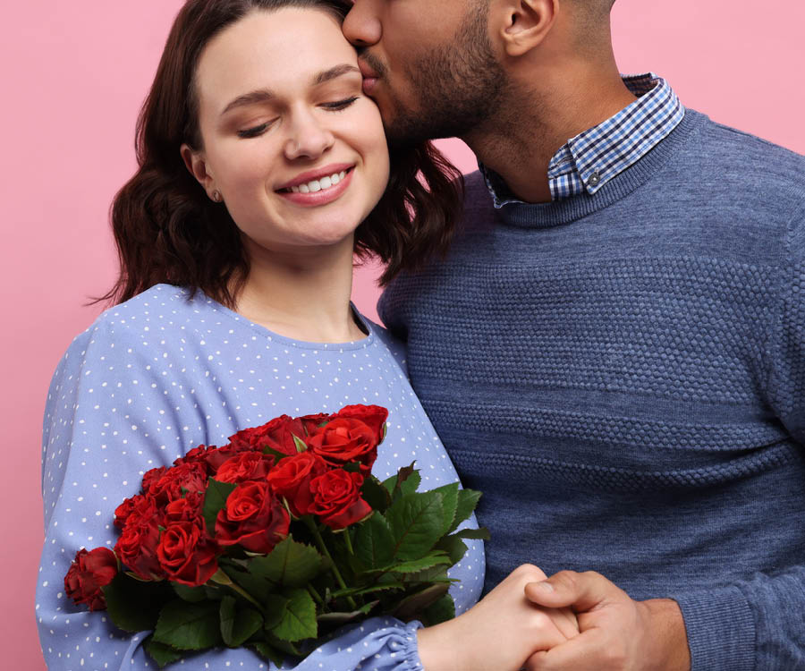Man embracing woman holding a bouquet of roses
