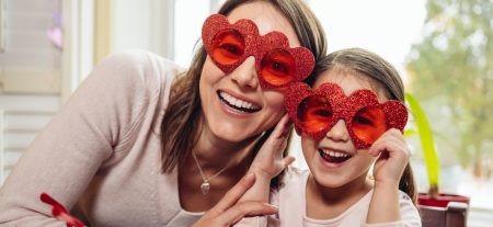 Mother and daughter wearing heart sun glasses, celebrating Valentine's day.