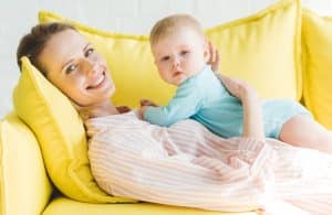 Mother relaxing on sofa with baby.