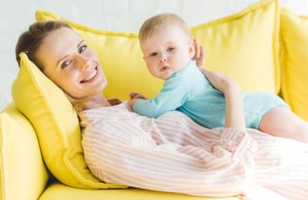 Mother relaxing on sofa with baby.