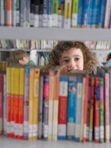 Child in library looking through book shelves