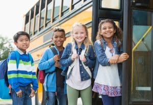 Kids smiling for a photo before getting on the bus school
